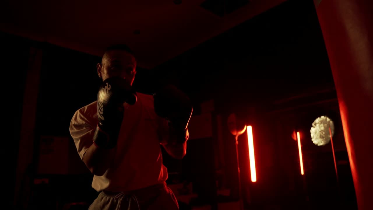A boxer shadowboxing in a dark, dramatically lit gym.