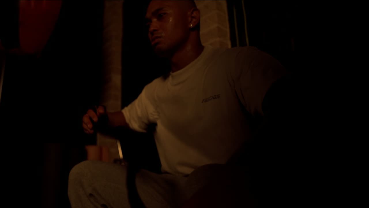 Bryan wrapping his hands in a dark, dramatically lit gym.